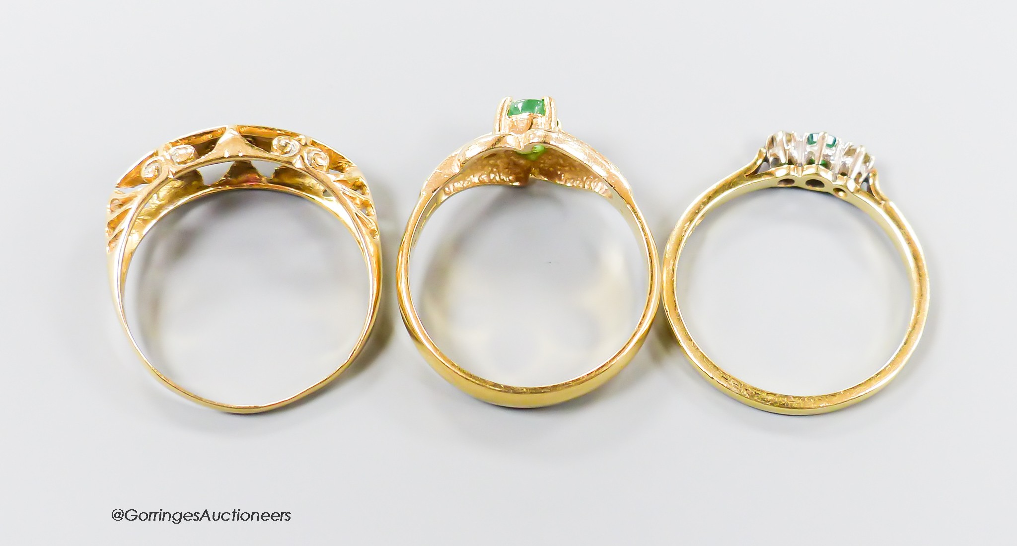 Three assorted modern 18ct gold and gem set rings, including emerald and diamond, both size M and ruby and diamond, size N gross 6.9 grams.